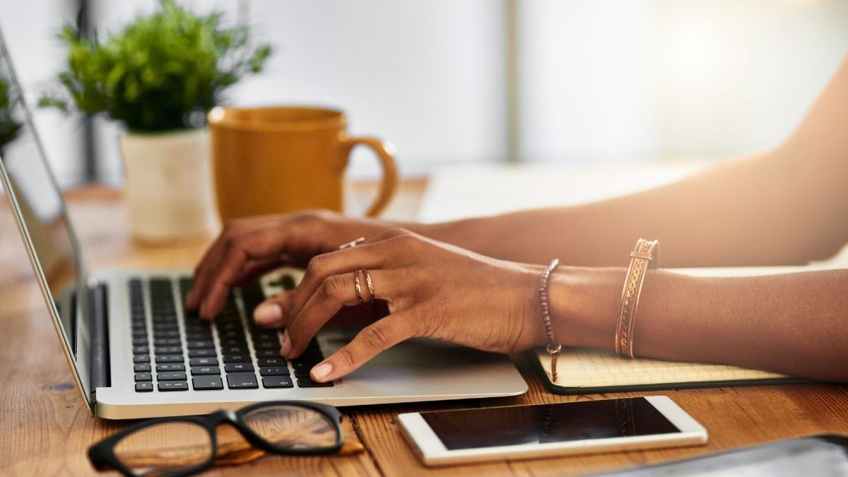 Hands type on keyboard with coffee mug in foreground as email user consider the AI ramifications of Gemini's use in Gmail.