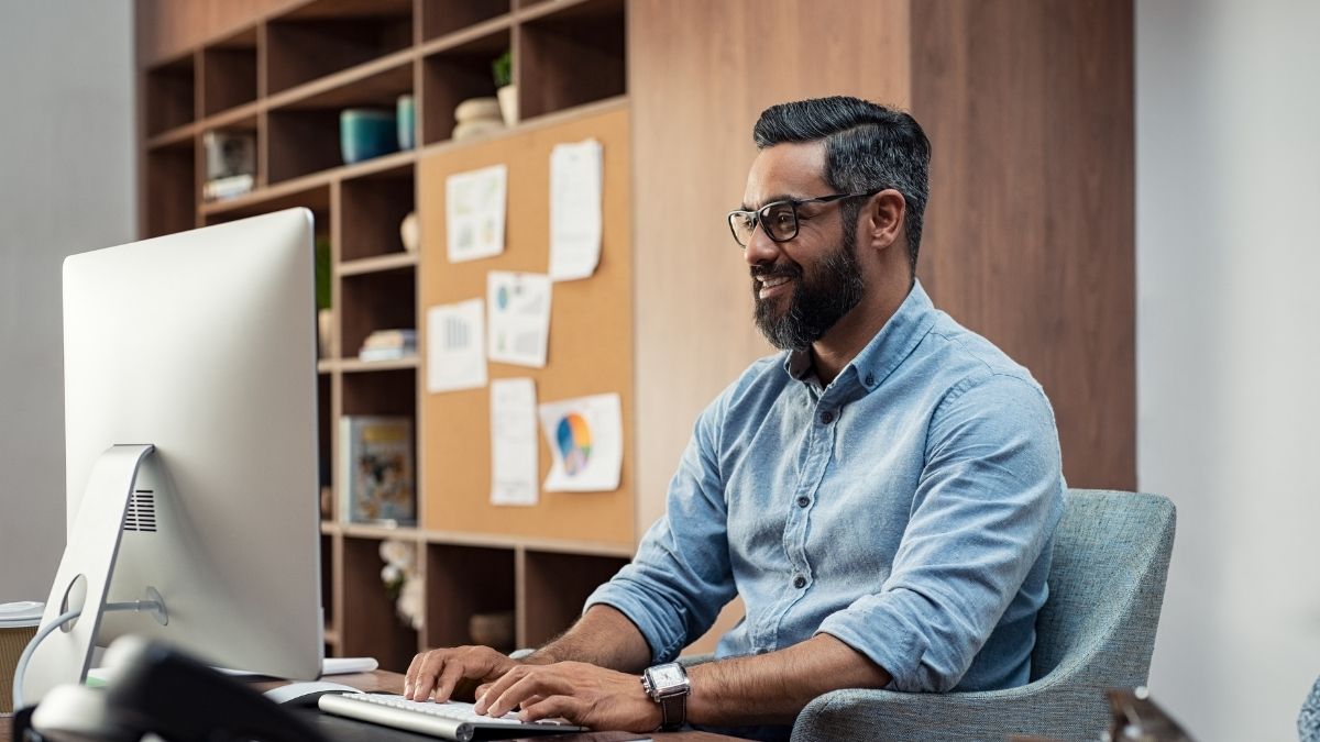 Asiatic, bespectacled man sits in front of a computer to validate emaisl behind secure email gateways.
